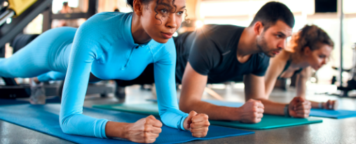 Fitnesskurs auf blauen Fitnessmatten üben eine Plank aus